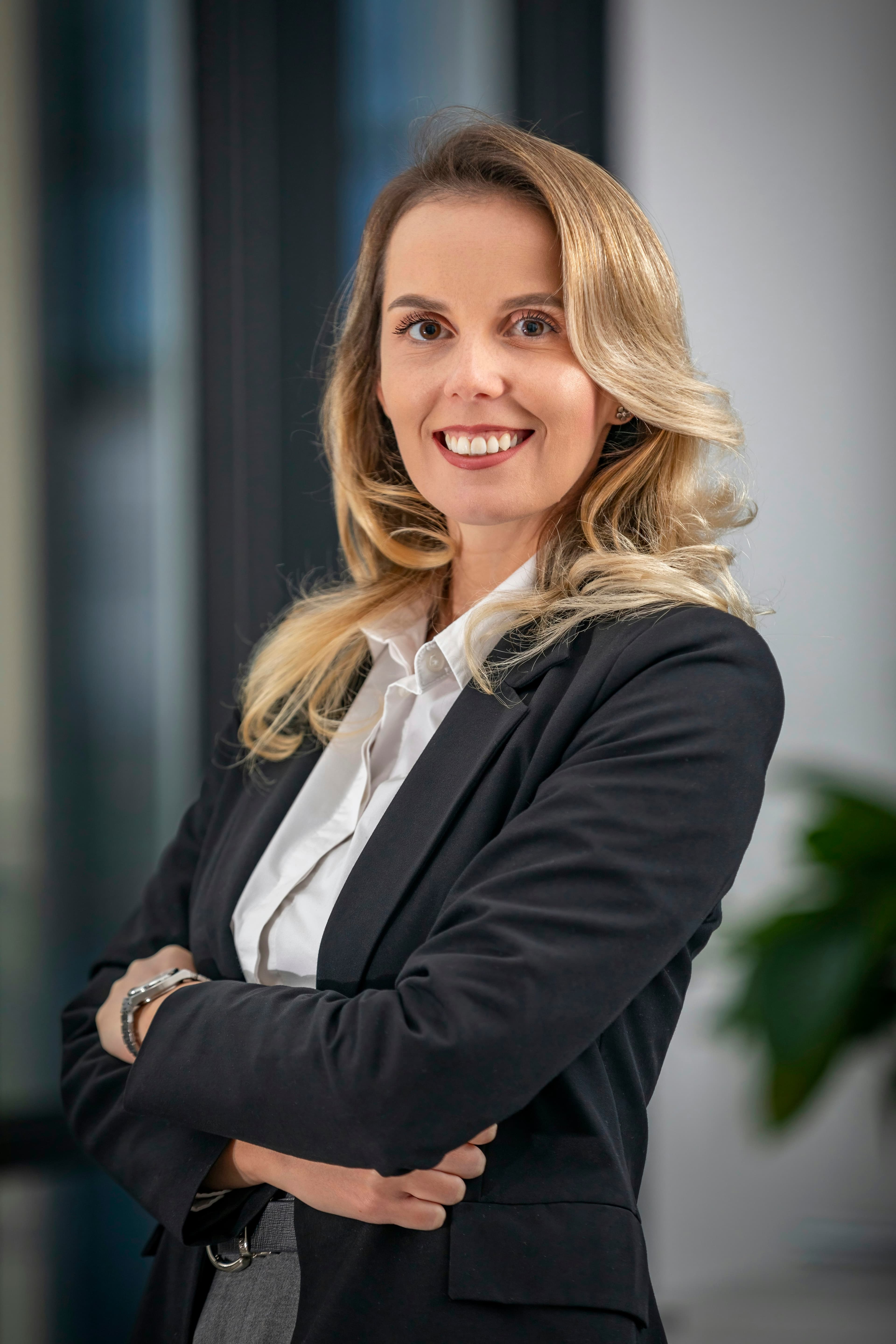 Professional woman in a tailored suit standing with arms folded